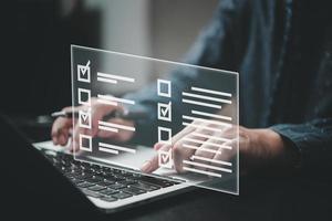 man using laptop questionnaire with checkbox, survey form online, answer questions in the exam of test business checklist and filling survey form online. photo