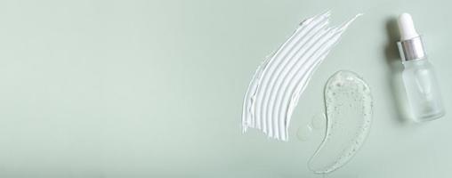 Cosmetic smears and pipette bottle on colored background top view. Banner format photo