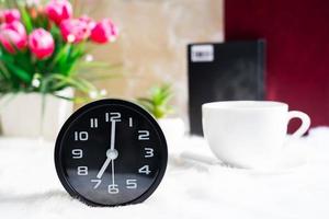 Black clock and cup of coffee photo