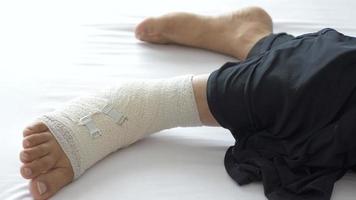 Person laying on bed with bandaged ankle video