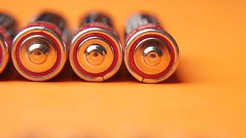 AA batteries lines up on orange background video