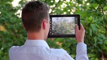 Teenager mit Touchpad, um an einem sonnigen Tag Fotos von Naturszenen zu machen