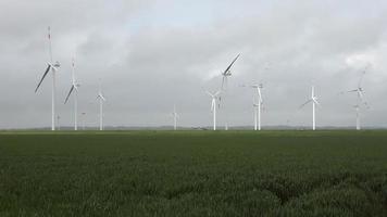 vista panorâmica sobre moinhos de vento de energia alternativa em um parque eólico com céu nublado. video