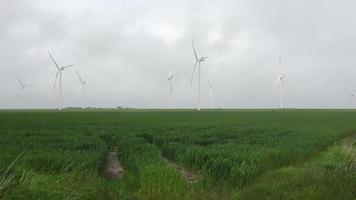 Panoramic view on alternative energy wind mills in a windpark with a cloudy sky.