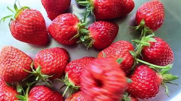 Slow motion of a strawberry falling on other strawberries on a chrome background. video