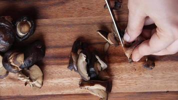 Slicing mushroooms on wood cutting board close up, funghi video