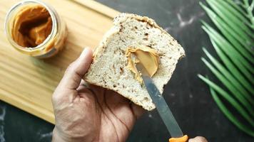 Spreading creamy peanut butter on slice of seeded bread video