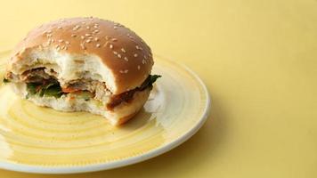 una hamburguesa a medio comer en un plato amarillo