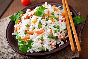 Appetizing healthy rice with vegetables in white plate on a wooden background. photo