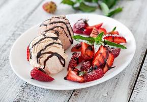 Ice cream with strawberries and chocolate on a white plate photo
