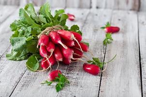 Fresh bunch of radishes on old wooden background photo