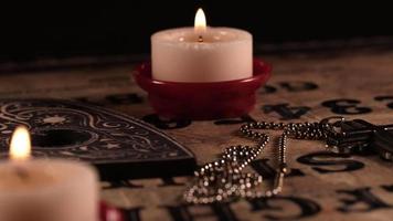 cruz de símbolo de religião cristã e tabuleiro de bruxa ouija à luz de velas video