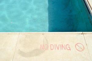 Red paint inscription no diving for safety on the background of the pool on a tropical warm sea resort and copy space photo