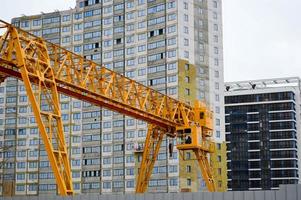 High heavy yellow metal iron load-bearing construction stationary industrial powerful gantry crane of bridge type on supports for lifting cargo on a modern construction site of buildings and houses photo