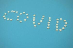 letters made of pills. medicines laid out the word coronavirus. white pills shot sideways on a blue background. volumetric inscription of white color in the form of a word. 2020 virus prophylaxis photo
