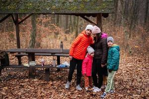 Mother with her kids having rest in autumn forest with roof shelter and picnic table. photo