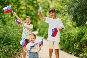 tres niños sostienen banderas eslovenas en el parque nacional triglav, eslovenia. foto