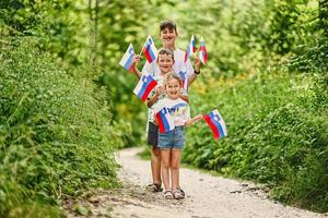 tres niños sostienen banderas eslovenas en el parque nacional triglav, eslovenia. foto