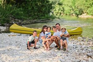 Family with four kids against canoe in rocky shore of a calm river in Triglav National Park, Slovenia. photo
