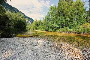 A yellow canoe rests on a rocky shore of a calm blue lake in Triglav National Park, Slovenia. photo