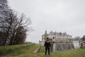 parte posterior del hombre turista con mochila visita el castillo de pidhirtsi, región de lviv, ucrania. foto