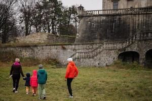 parte posterior de la madre con cuatro hijos visita el castillo de pidhirtsi, región de lviv, ucrania. turista familiar. foto