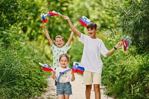 tres niños sostienen banderas eslovenas en el parque nacional triglav, eslovenia. foto