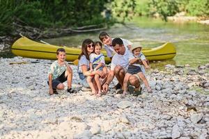 Family with four kids against canoe in rocky shore of a calm river in Triglav National Park, Slovenia. photo