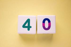 Close-up photo of a white plastic cubes with a colorful number 40 on a yellow background. Object in the center of the photo