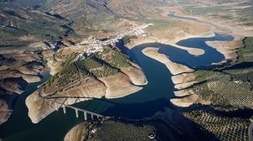 Aerial drone view of Iznajar white villages of Andalucia in Spain with low levels of water in the reservoir. Touristic destination. Holidays and vacation. Dry season in the Iberian Peninsula. photo