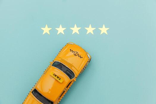 Yellow toy car Taxi Cab and 5 stars rating isolated on blue background. Smartphone application of taxi service for online searching calling and booking cab concept. Taxi symbol. Copy space. photo