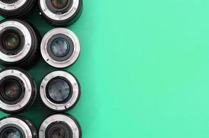 Several photographic lenses lie on a bright turquoise background. Copy space photo