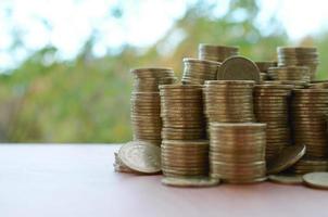 Big amount of shiny ukrainian old 1 hryvnia coin stacks close up on wooden table on green trees backdrop. The concept of business and rich life in Ukraine photo