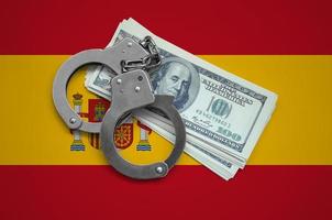 Spain flag  with handcuffs and a bundle of dollars. Currency corruption in the country. Financial crimes photo