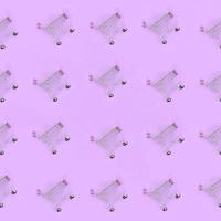 Shopping addiction, shopping lover or shopaholic concept. Many small empty shopping carts perform a pattern on a pastel colored paper background. Flat lay composition, top view photo