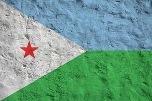 Djibouti flag depicted in bright paint colors on old relief plastering wall. Textured banner on rough background photo