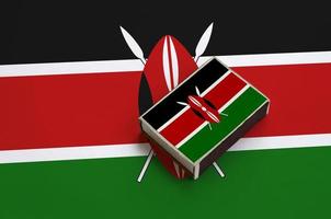 Kenya flag  is pictured on a matchbox that lies on a large flag photo