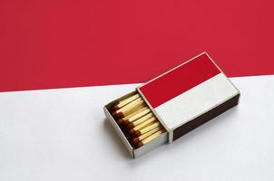 Monaco flag  is shown in an open matchbox, which is filled with matches and lies on a large flag photo