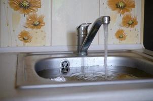 Stainless steel sink plug hole close up full of water and particles of food photo