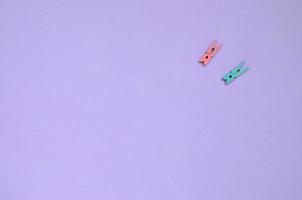Two colored wooden pegs lie on texture background of fashion pastel violet color paper in minimal concept photo