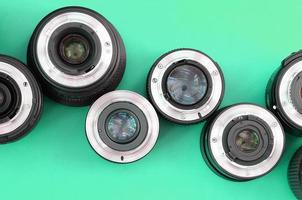 Several photographic lenses lie on a bright turquoise background. Copy space photo