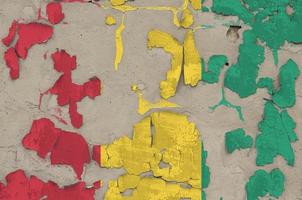 Guinea flag depicted in paint colors on old obsolete messy concrete wall closeup. Textured banner on rough background photo