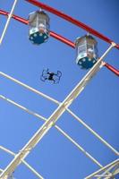 Drone take off from land and flying for take photo front of ferris wheel
