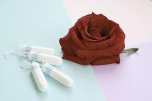Menstrual pads and tampons with red rose flower on multicolored background photo