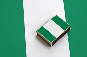 Nigeria flag  is pictured on a matchbox that lies on a large flag photo