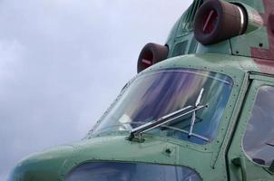 Helicopter cabin fragment close up. Camouflage aircraft fuselage and bulletproof glass photo