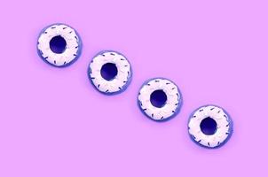 Many small plastic donuts lies on a pastel colorful background. Flat lay minimal pattern. Top view photo