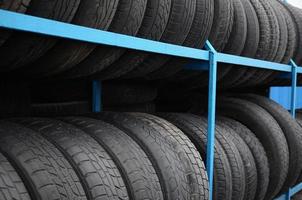 Rack with variety of car tires in automobile store. Many black tires. Tire stack background photo