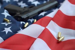 Las balas de 9 mm y la pistola se encuentran en la bandera de los Estados Unidos doblada foto