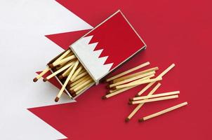 Bahrain flag  is shown on an open matchbox, from which several matches fall and lies on a large flag photo